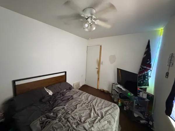 a bedroom with a bed and a flat tv screen on the dresser