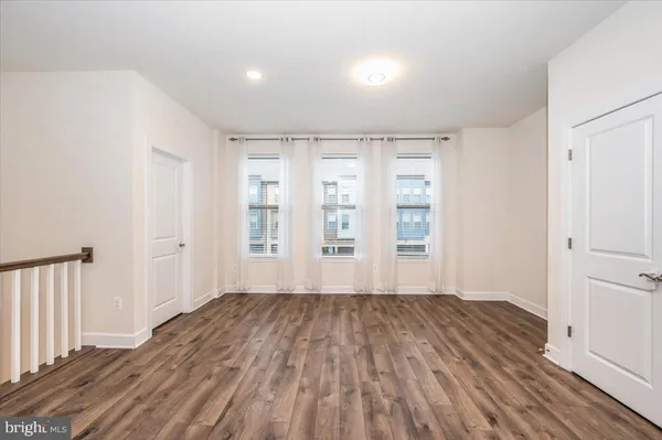 a kitchen with stainless steel appliances kitchen island granite countertop a refrigerator a stove top oven a sink dishwasher and white cabinets with wooden floor