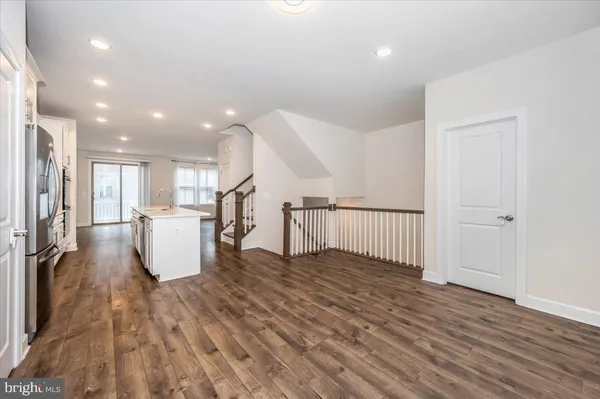 a kitchen with stainless steel appliances kitchen island a stove a sink and a refrigerator with wooden floor