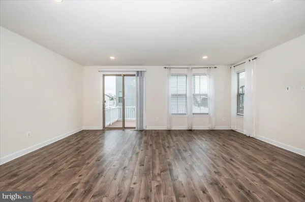 a view of an empty room with wooden floor and glass door