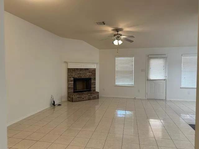 a view of a livingroom with a fireplace a ceiling fan and windows