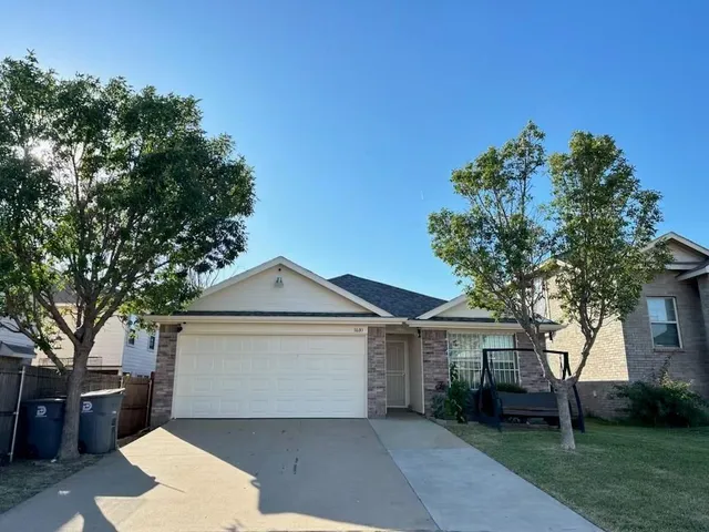 a front view of a house with a garden and trees