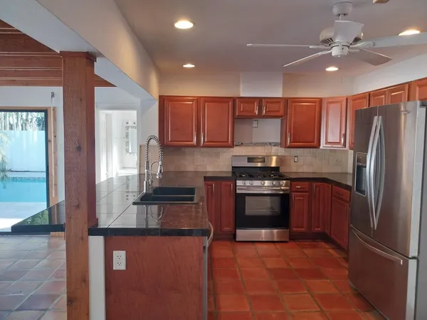 a kitchen with stainless steel appliances granite countertop a refrigerator a stove and a sink