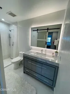 a bathroom with a granite countertop sink a toilet and a large mirror