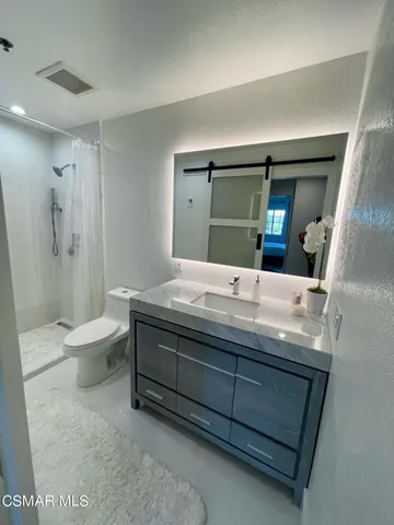 a bathroom with a granite countertop sink a toilet and a large mirror