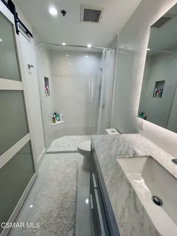 a en suite bathroom with a granite countertop sink and a mirror