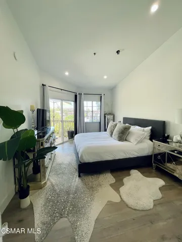 a spacious bedroom with a bed a large window and potted plant on the table