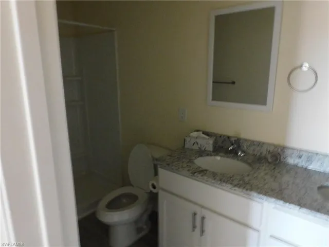 a bathroom with a granite countertop shower and a toilet