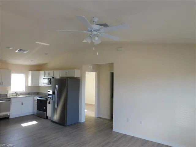 a kitchen with stainless steel appliances granite countertop a refrigerator a sink dishwasher and a stove with wooden floor