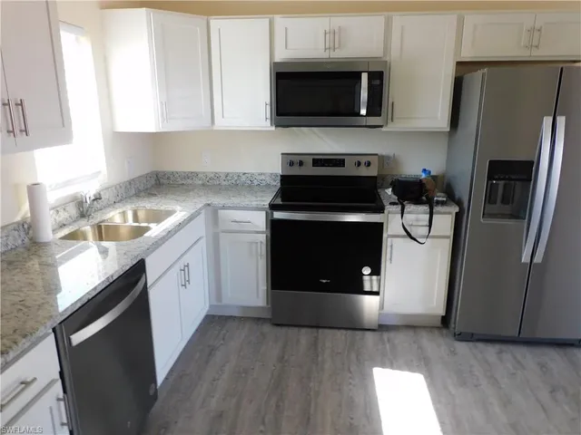 a kitchen with stainless steel appliances granite countertop a refrigerator a sink and a stove