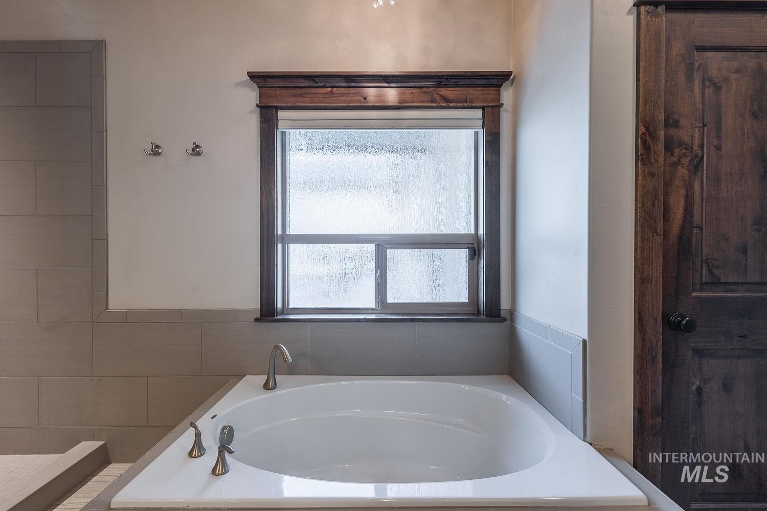8077 Star Pass Ridge Road Nampa, ID 83686 - Photo 25 of 37 Soaking tub with bronze fixtures, framed by a window with privacy glass and a wood trim