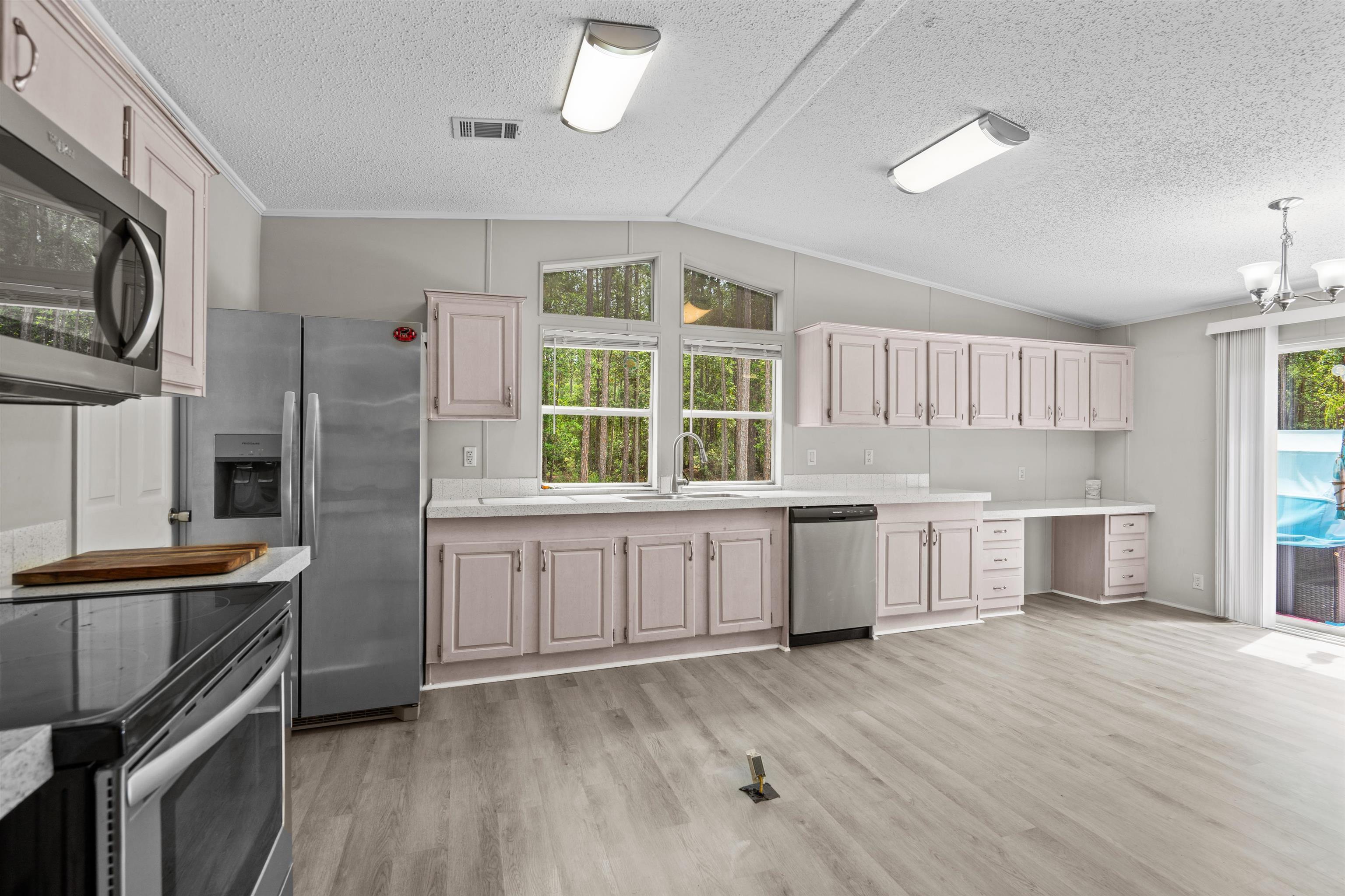 2130 Carter Road St. Augustine, FL 32084 - Photo 15 of 67 Kitchen featuring stainless steel appliances, light wood-style floors, a textured ceiling, crown molding, and suspended lighting