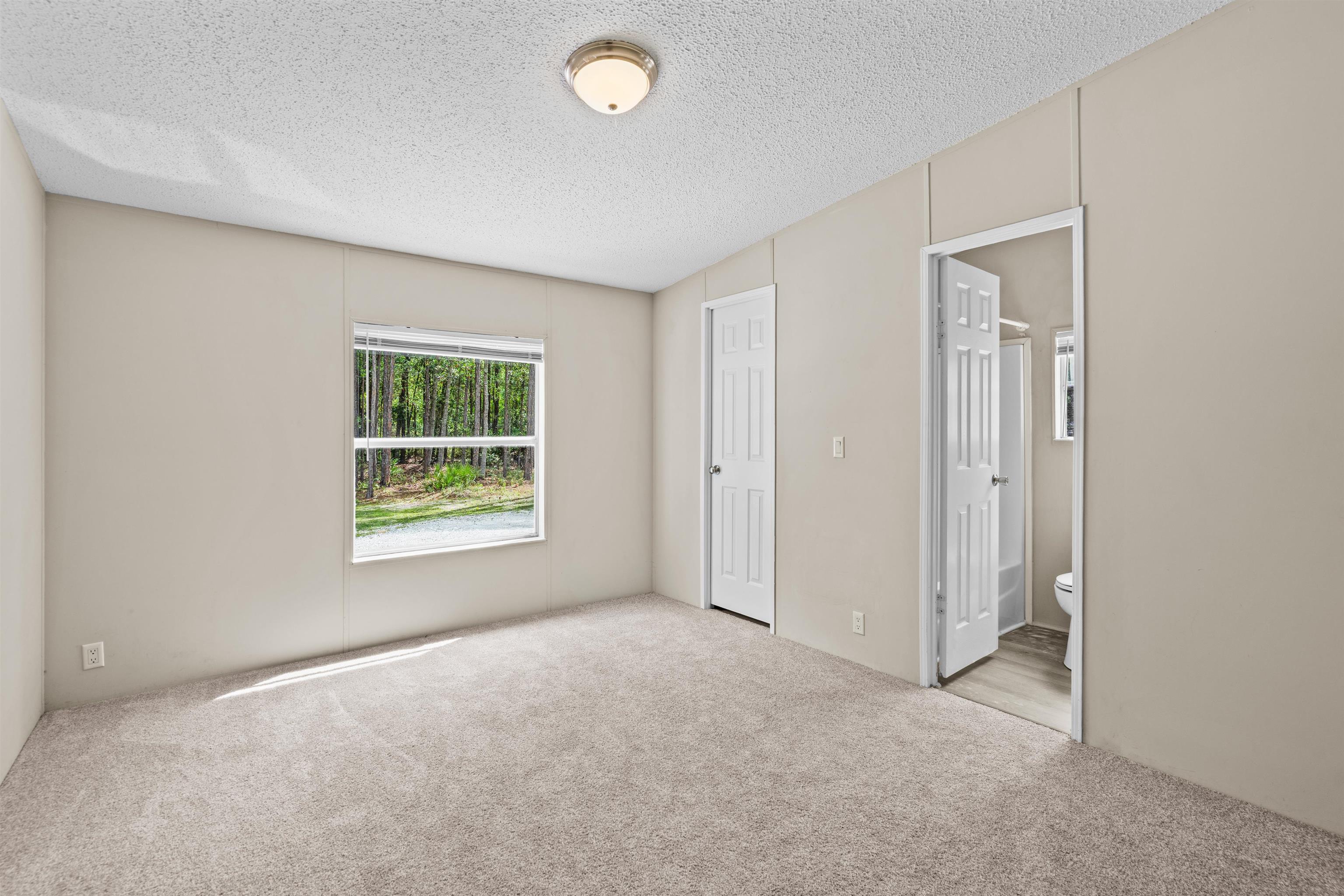 2130 Carter Road St. Augustine, FL 32084 - Photo 28 of 67 Unfurnished bedroom featuring a textured ceiling, light colored carpet, and ensuite bath