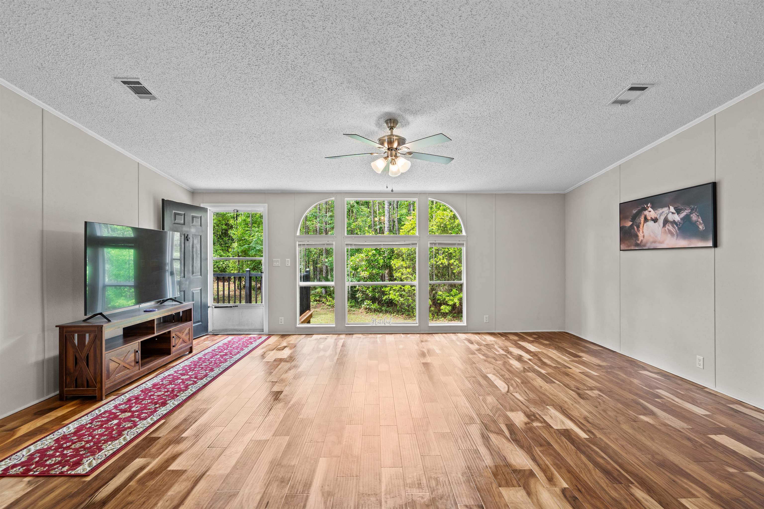 2130 Carter Road St. Augustine, FL 32084 - Photo 8 of 67 Unfurnished living room featuring a decorative wall, light wood-style flooring, a ceiling fan, crown molding, and a textured ceiling