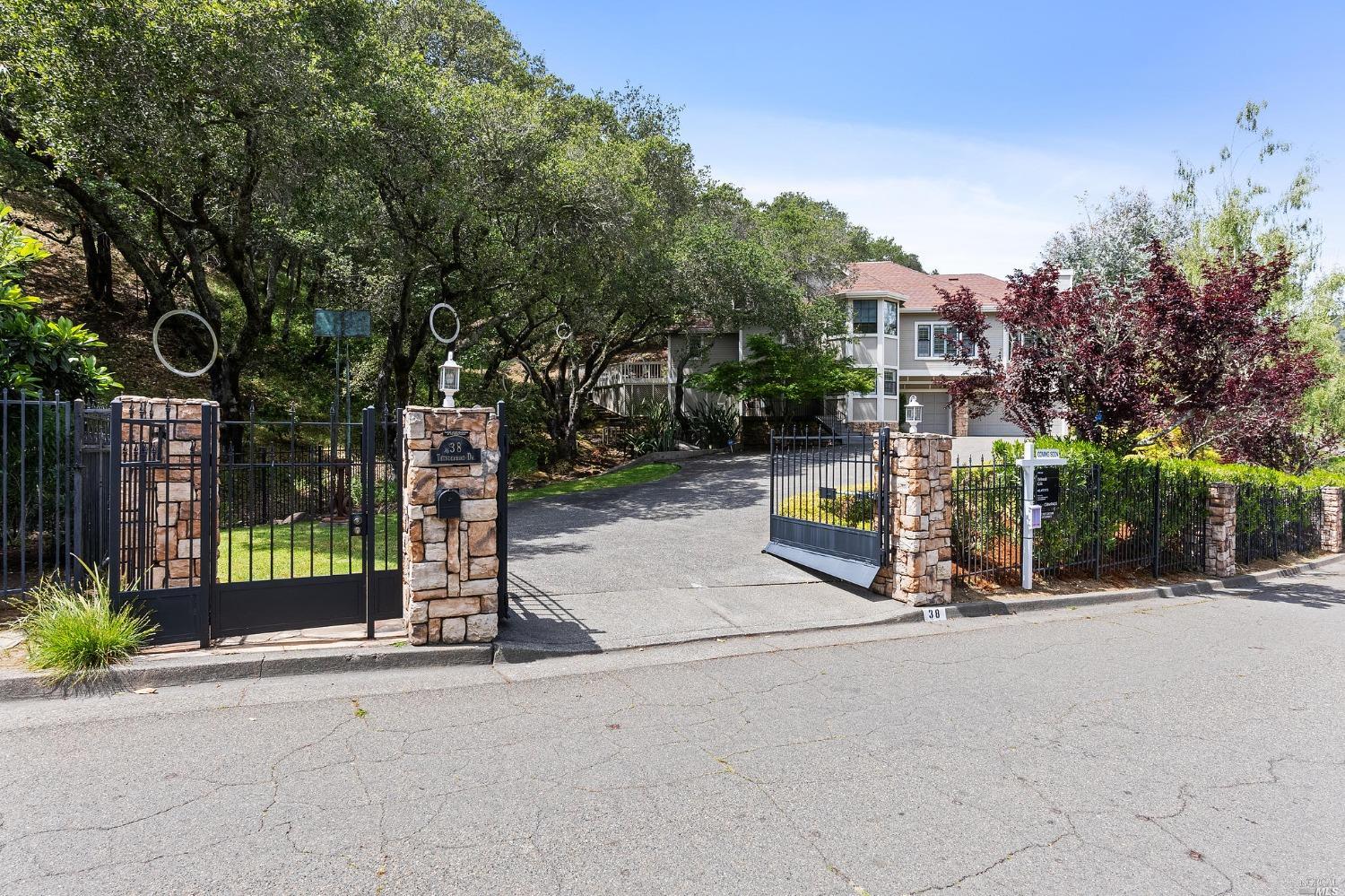 Stately gated entry w/ stainless steel sculptures displayed in the oak trees.