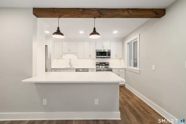 a view of kitchen with stainless steel appliances wooden floor and window