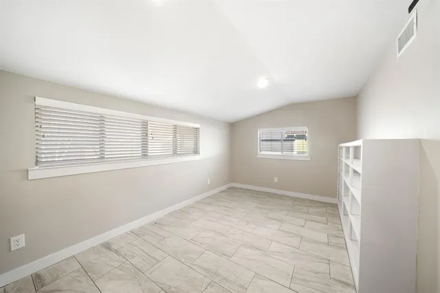 an empty room with a window and a refrigerator