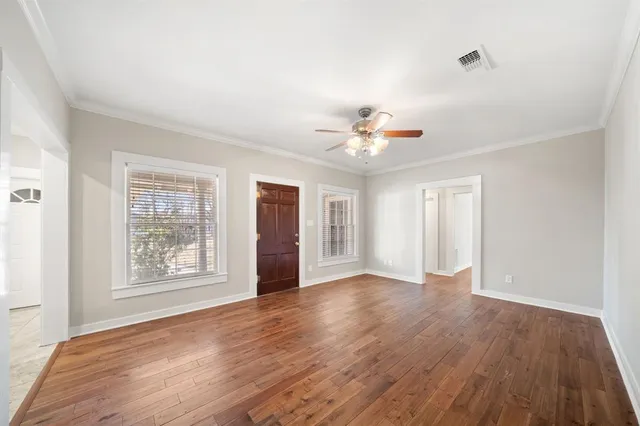 an empty room with wooden floor chandelier and windows
