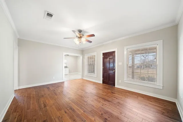 a view of an empty room with wooden floor and a window
