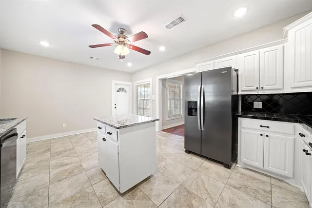 a kitchen with granite countertop a refrigerator a sink and cabinets