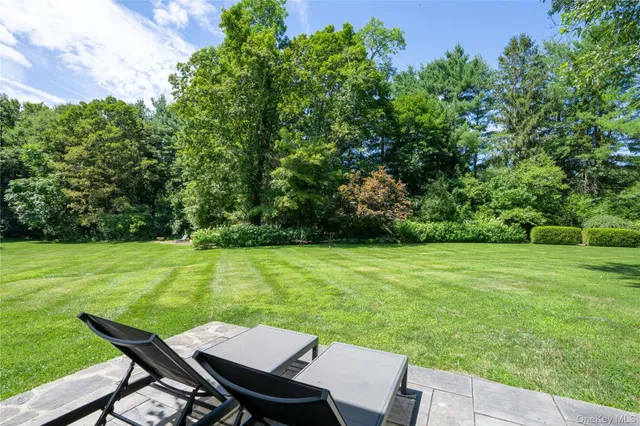 a backyard of a house with table and chairs under an umbrella