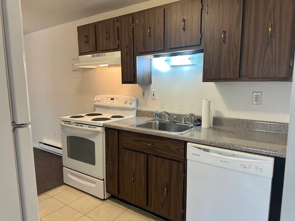 a kitchen with granite countertop wood cabinets and white appliances