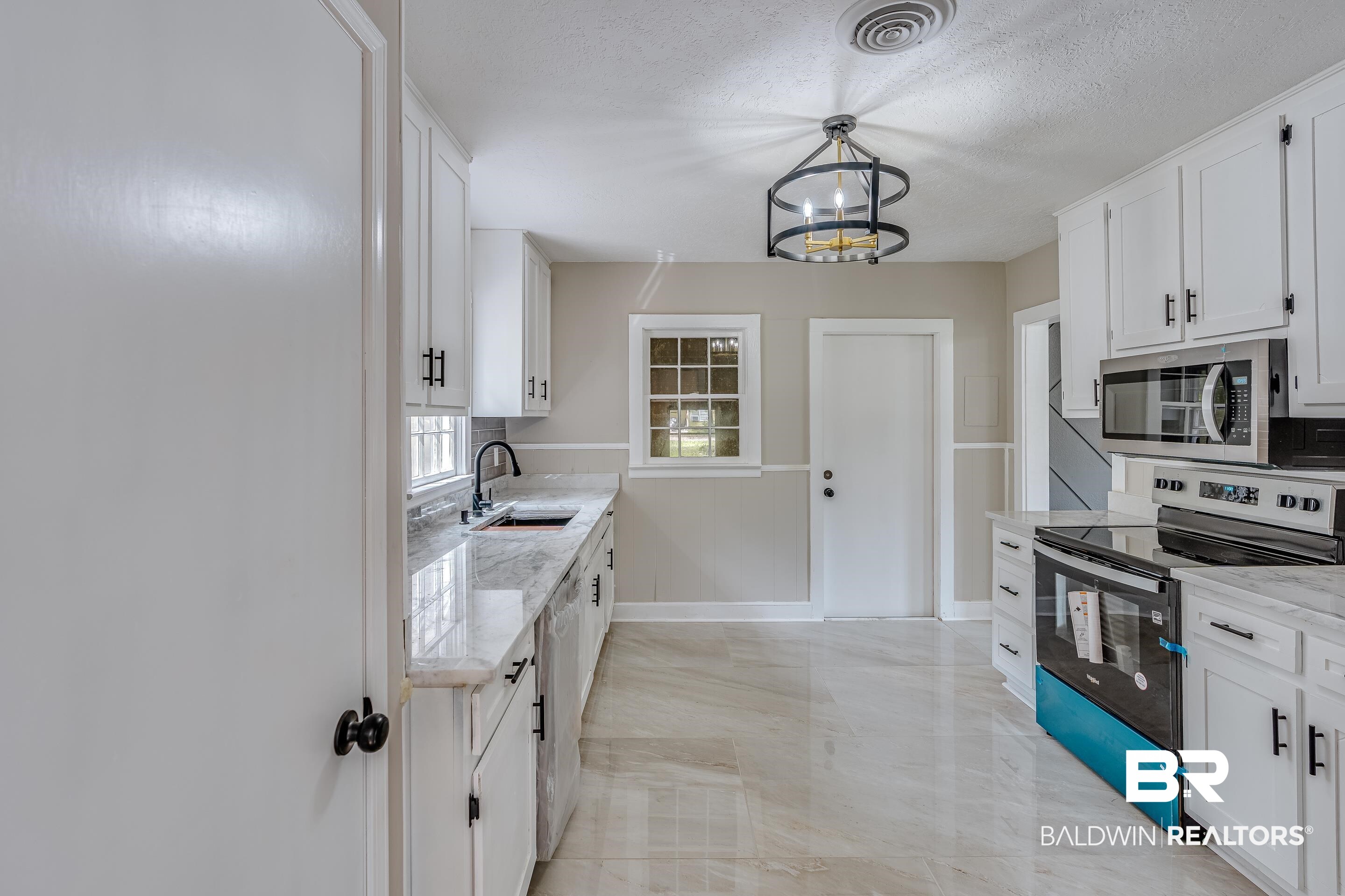 8001 16th Street Irvington, AL 36544 - Photo 13 of 35 Kitchen with appliances with stainless steel finishes, white cabinets, hanging light fixtures, a textured ceiling, and light stone countertops