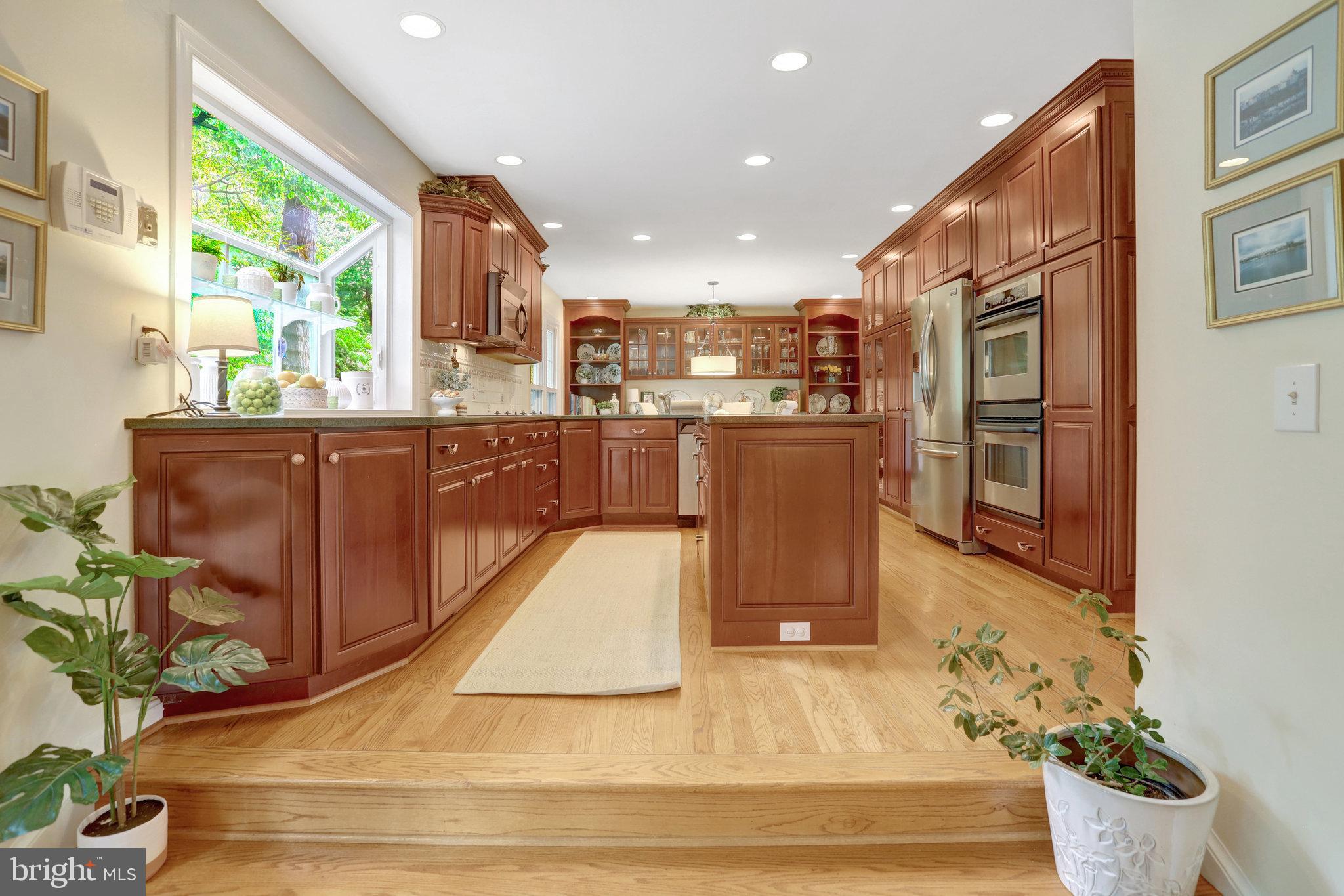 7006 Maple Tree Lane Springfield, VA 22152 - Photo 4 of 49 a kitchen with stainless steel appliances kitchen island granite countertop a refrigerator a stove top oven and a potted plant