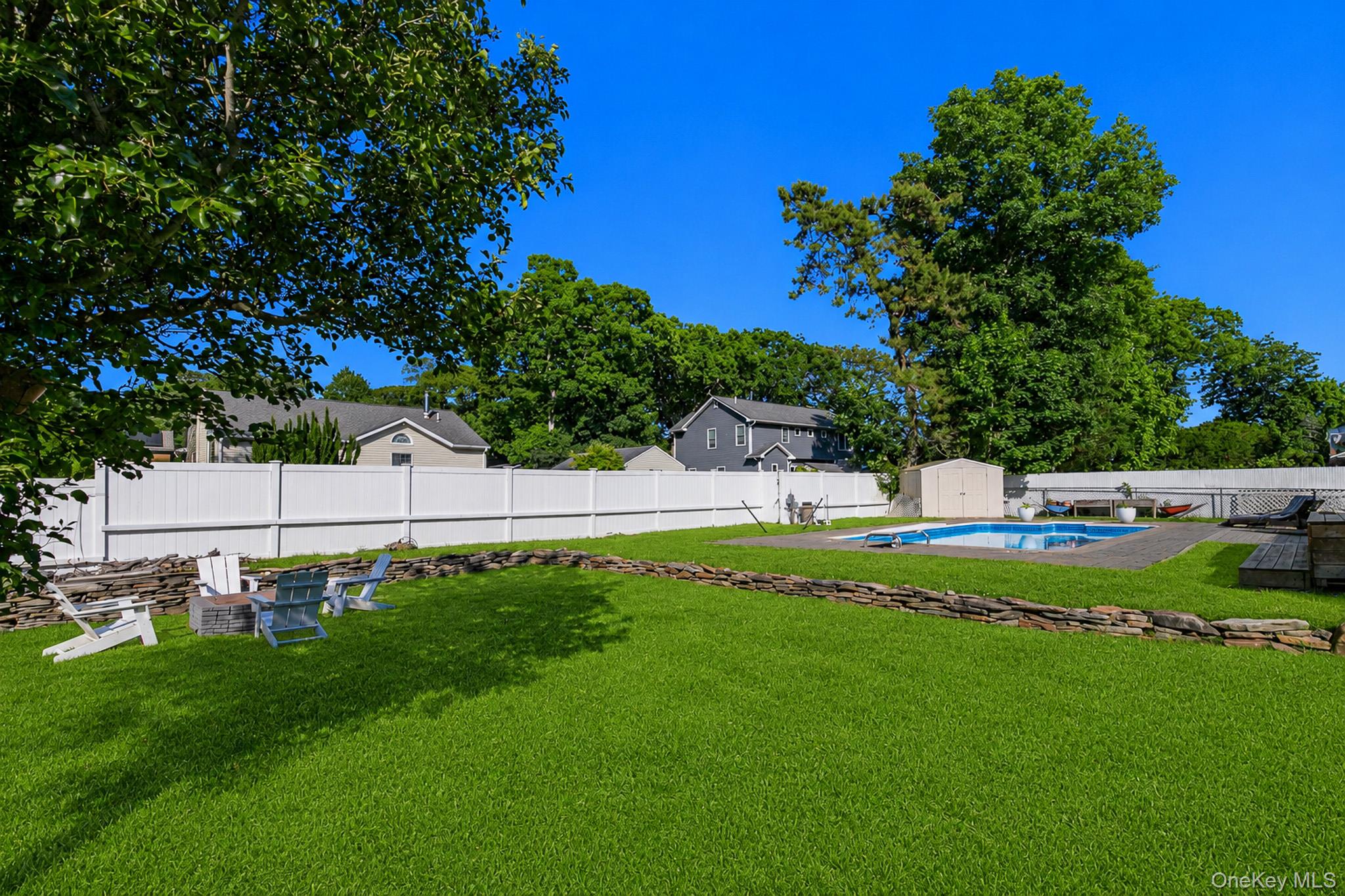 33 Lillian Road Nesconset, NY 11767 - Photo 38 of 42 The Large Fully PVC Fenced Backyard Has Beautiful Stone/Rock Walls, Expansive Lawns/Beautiful Grasses With Ample Room For Entertaining, And A Firepit Area.