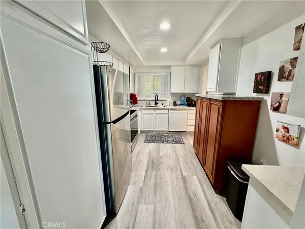 a view of a kitchen with refrigerator and wooden floor