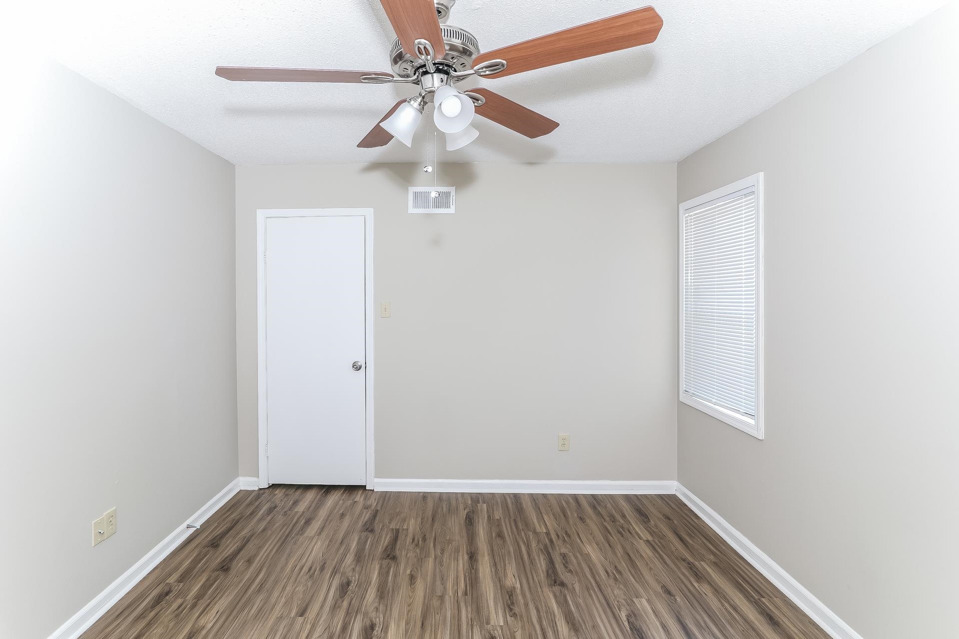 6076 Elk Grove Road Memphis, TN 38115 - Photo 8 of 15 an empty room with wooden floor fan and windows
