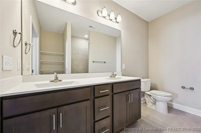 a bathroom with a double vanity sink toilet and mirror