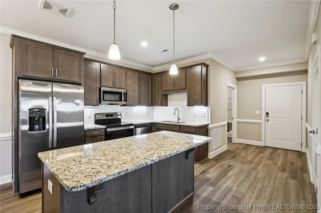a large kitchen with kitchen island a large counter top a sink stainless steel appliances and cabinets