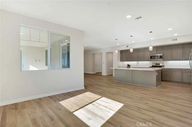 a large white kitchen with kitchen island a stove a sink dishwasher and a refrigerator with wooden floor