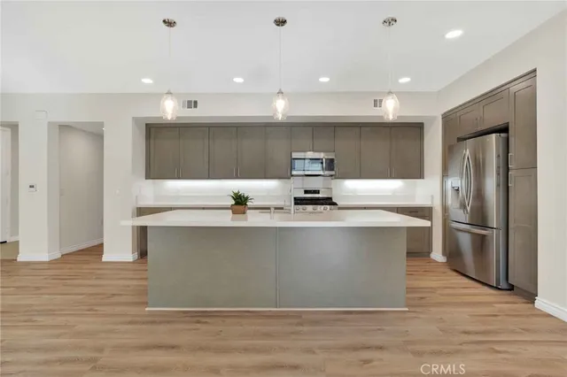 a kitchen with kitchen island stainless steel appliances a sink and a refrigerator