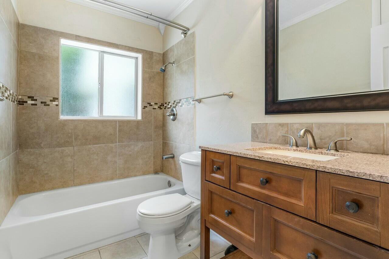 121 Northeast Spanish Court Boca Raton, FL 33432 - Photo 21 of 36 a bathroom with a granite countertop toilet sink and mirror
