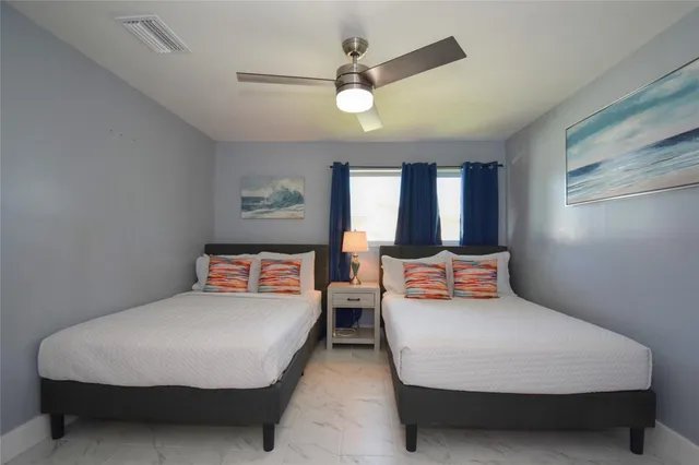 a bedroom with two beds and ceiling fan