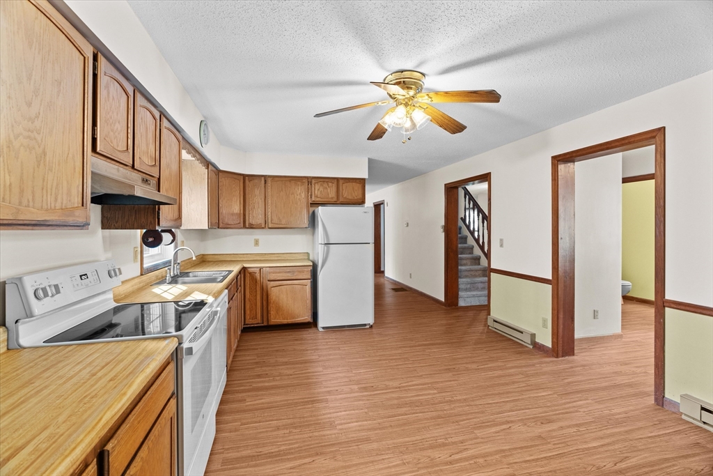 102 Valley Road Barre, MA 01005 - Photo 5 of 40 a kitchen with stainless steel appliances granite countertop a refrigerator a stove top oven a sink dishwasher and white cabinets with wooden floor
