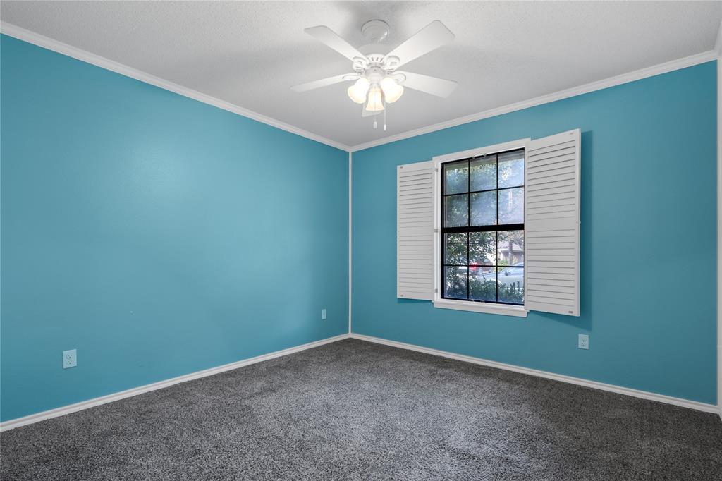 1609 Robin Street Mineola, TX 75773 - Photo 15 of 24 Room featuring a window with white louvered shutters, ceiling fan with light fixture, textured ceiling, and gray carpet