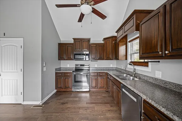 a kitchen with stainless steel appliances granite countertop a sink a stove top oven a granite counter space and cabinets