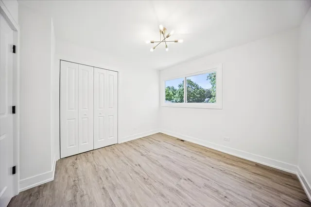 an empty room with wooden floor chandelier fan and windows