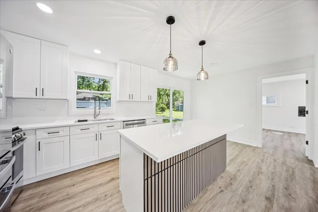 a kitchen with kitchen island a sink dishwasher a stove and a refrigerator with wooden floor