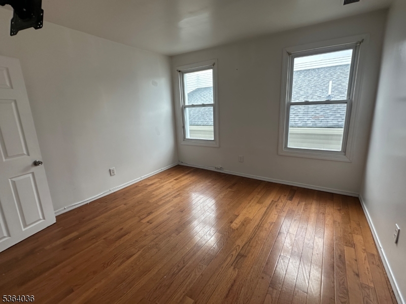 348 13th Avenue, Unit 3 Newark, NJ 07103 - Photo 11 of 14 a view of an empty room with wooden floor and a window