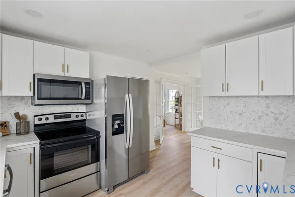 a kitchen with white cabinets a sink dishwasher and a stove with wooden floor