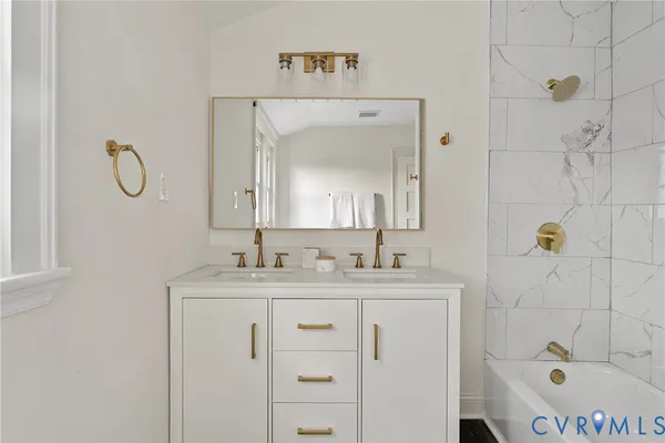 a bathroom with a sink vanity granite tub shower and a mirror