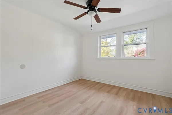 an empty room with wooden floor closet and ceiling fan