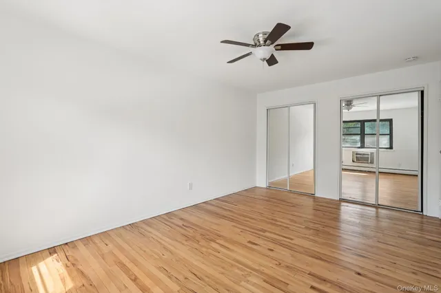 a view of empty room with wooden floor and ceiling fan