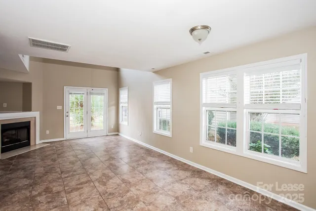a view of an empty room with a window and fire place