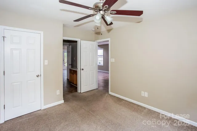 an empty room with a ceiling fan and closet area