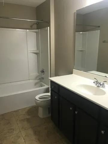 a bathroom with a bathtub shower sink vanity and toilet